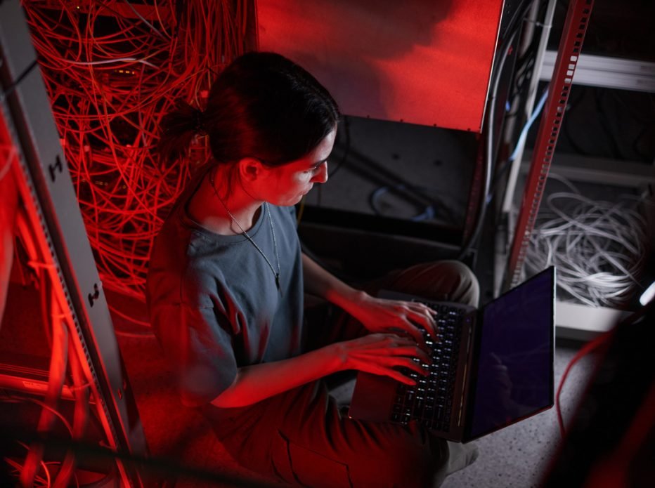 Engineer working on a laptop in a comms room