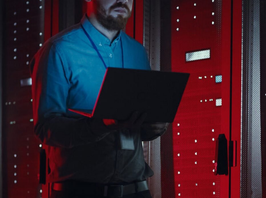 Engineer with a laptop beside server racks