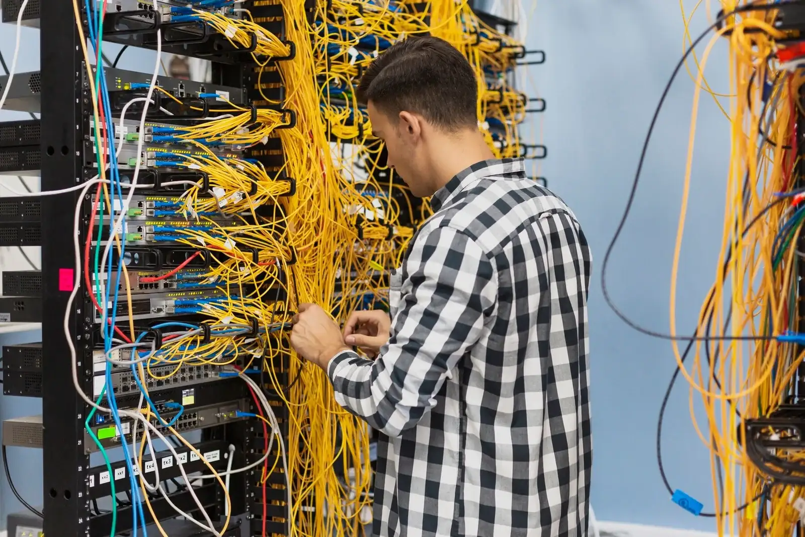 Engineer patching fibre in a comms rack